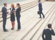 Business professionals in suits on steps, some talking, one on phone, one with briefcase.