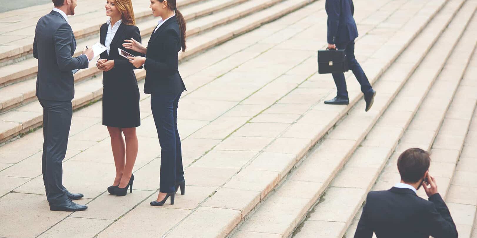 people_23 Business professionals in suits on steps, some talking, one on phone, one with briefcase.