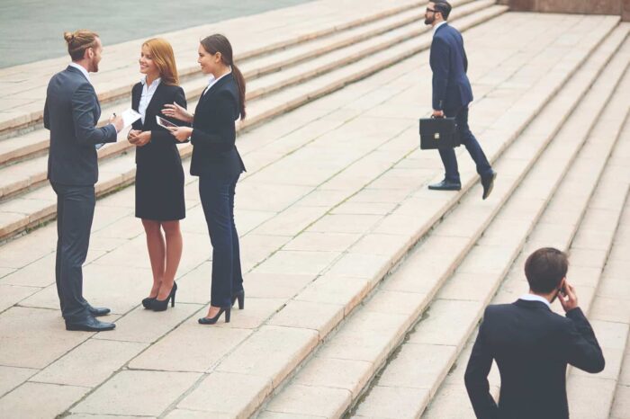 people_23 Business professionals in suits on steps, some talking, one on phone, one with briefcase.